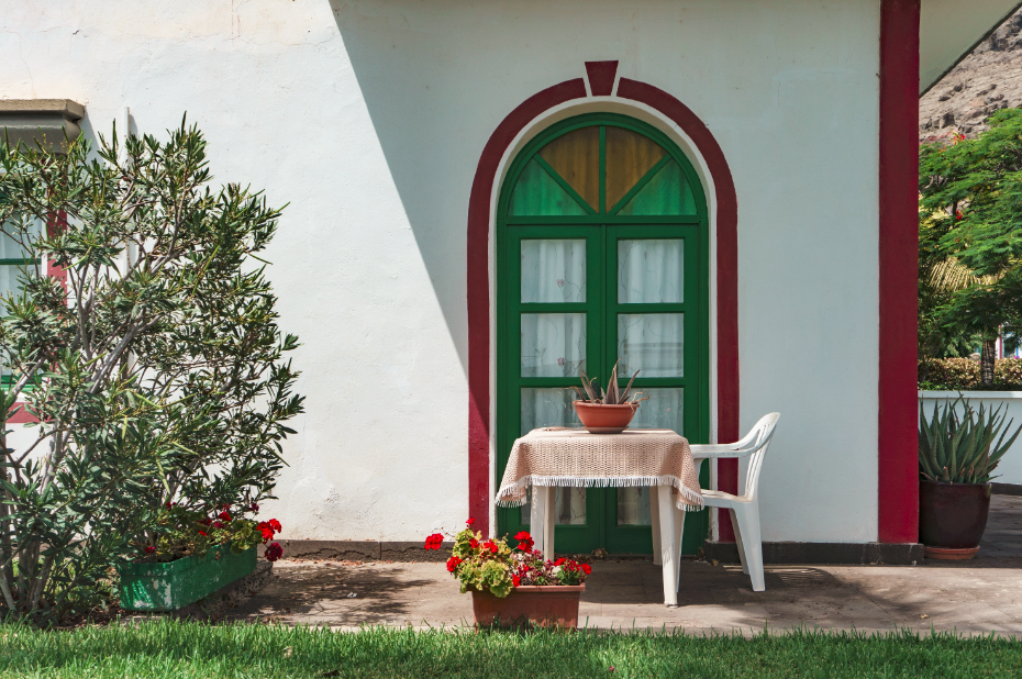 Devant de maison en bord de mer avec table de jardin et fleurs rouges