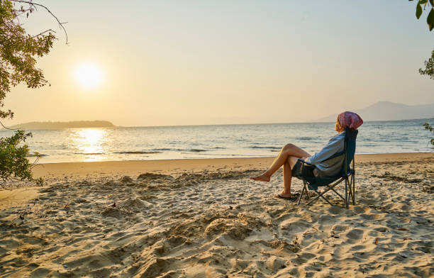 Femme sur un stransat au soleil à la plage en vacances